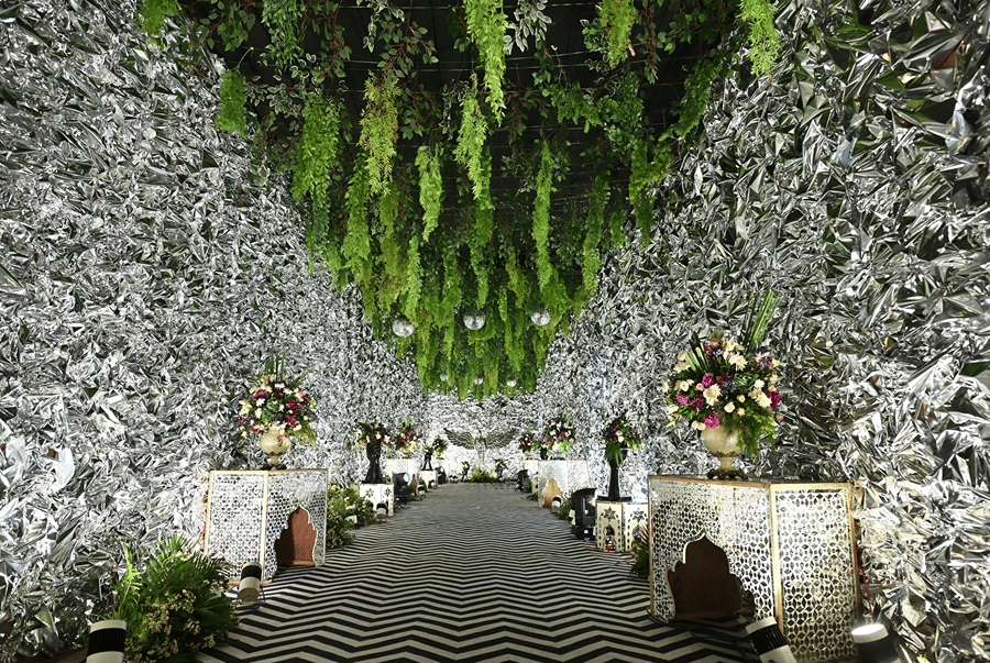 Banquet hallway with a zig-zag floor, floral walls and hanging greenery at Lime Tree Hotel & Banquet, Jaipur