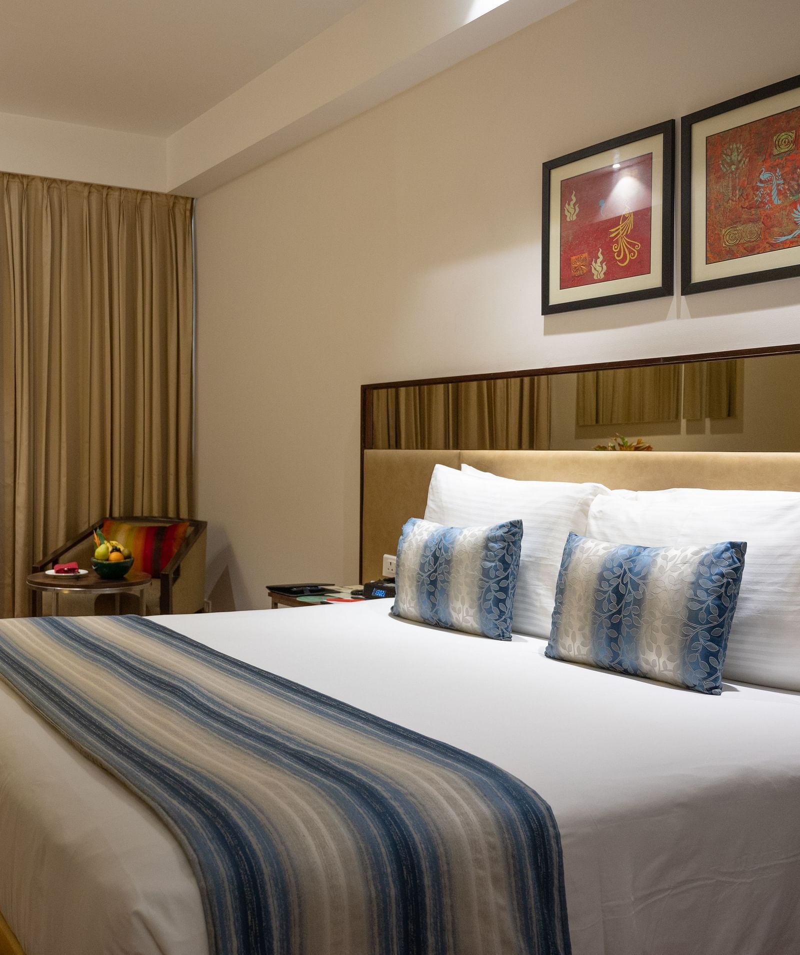 An image of a bedroom with working table and a chair at long shot view of the hotel corridors at Grand Kakinada by GRT Hotels