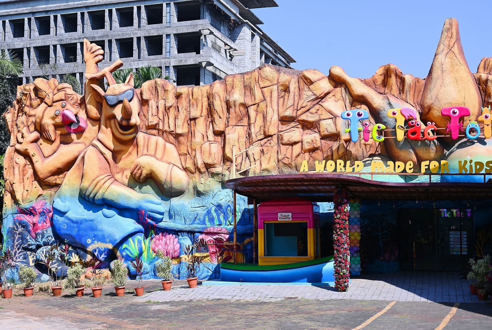 Outdoor play area with a large, colourful rock-themed structure and a bouncy castle entrance inside Water Kingdom.
