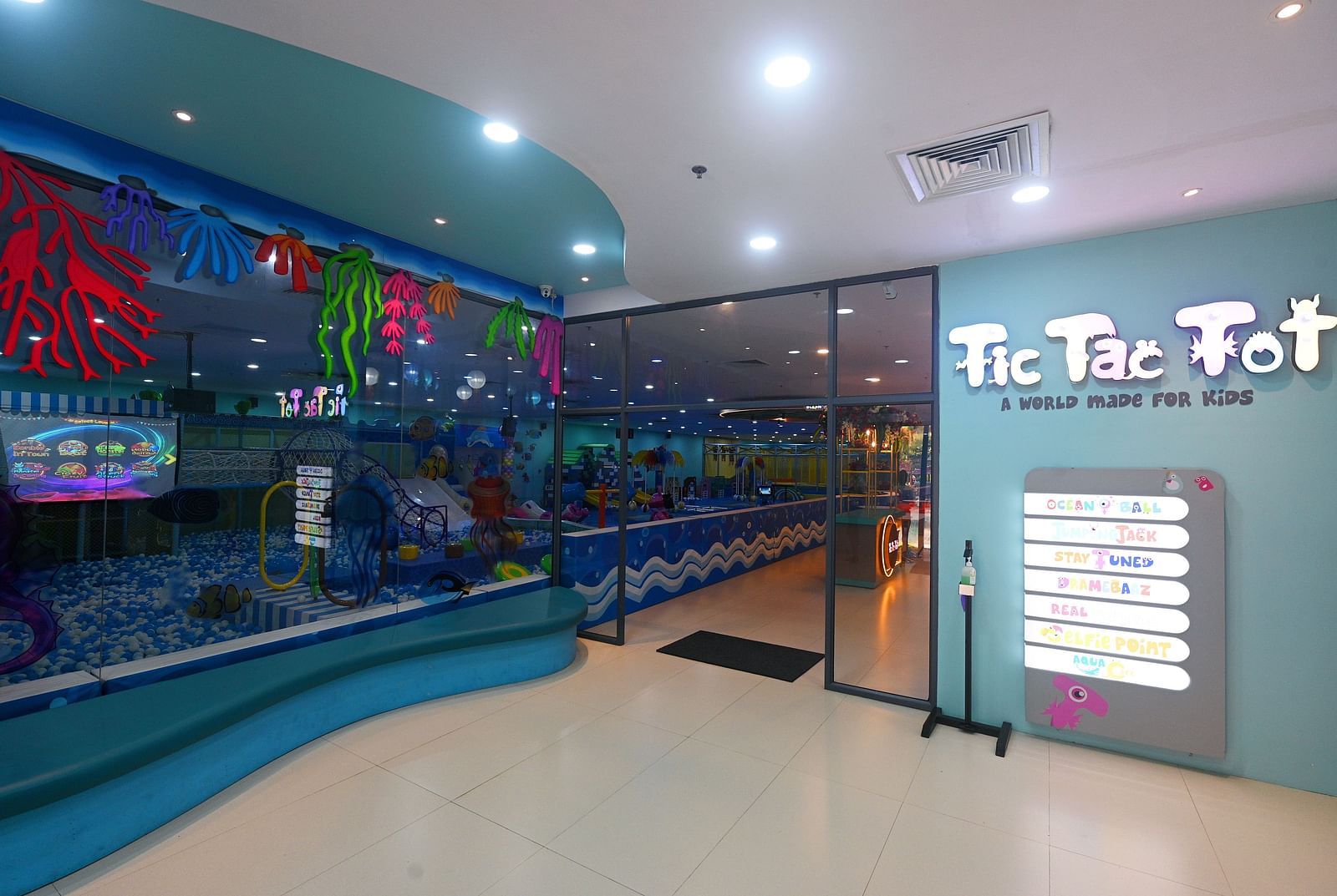 Indoor play area with a Tic Tac Tot sign, a door, and a painted mural on the wall - Water Kingdom.