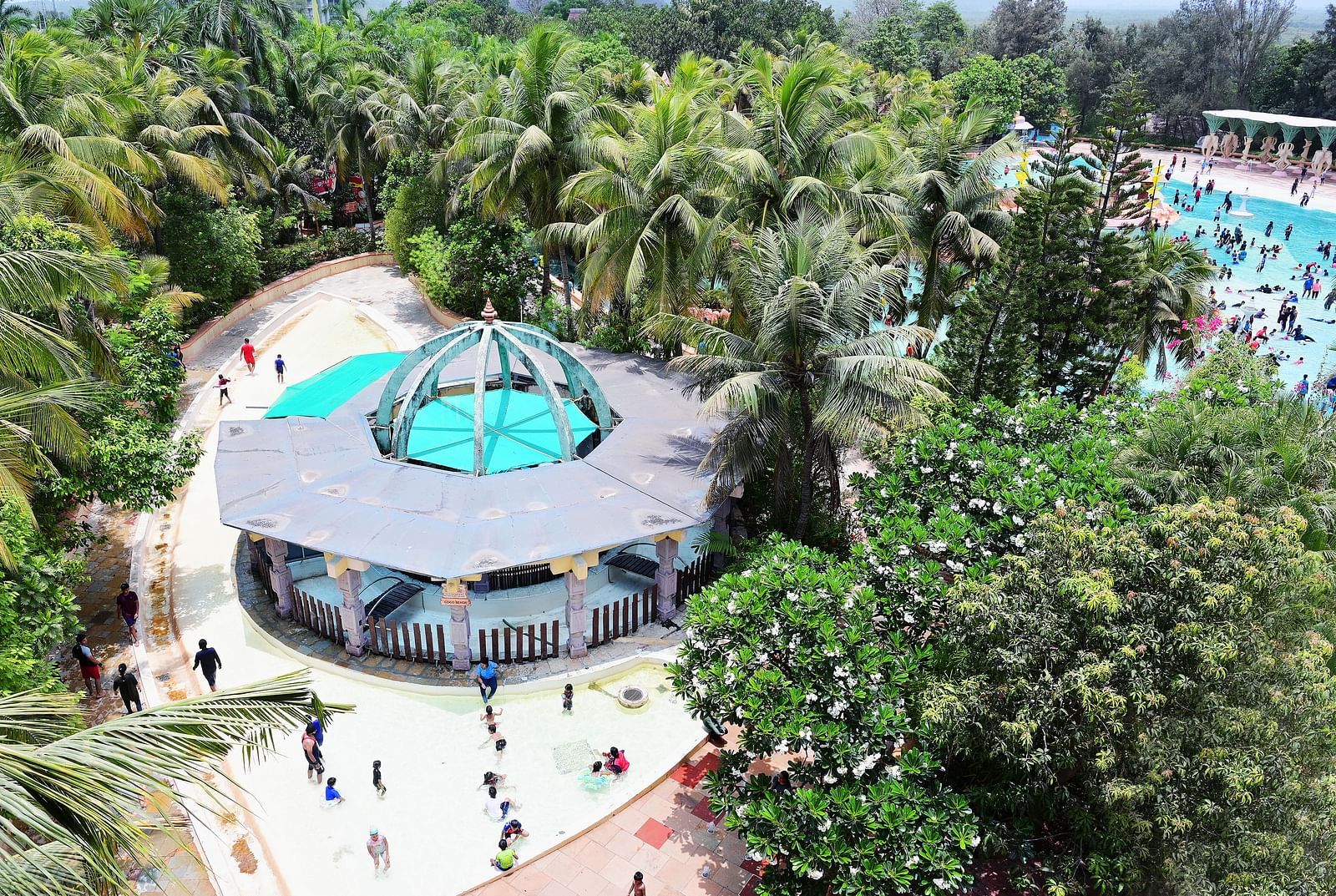 Aerial view of a circular pool with slides and a central structure, surrounded by trees.