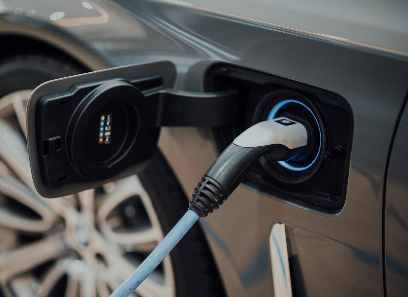 Close-up of an electric vehicle being charged, showing the charging plug connected to the car’s port.
