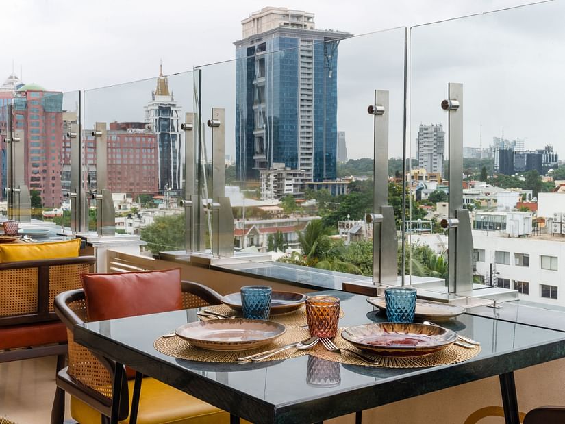 Rooftop restaurant with city skyline views and neatly set dining tables arranged along the railing.