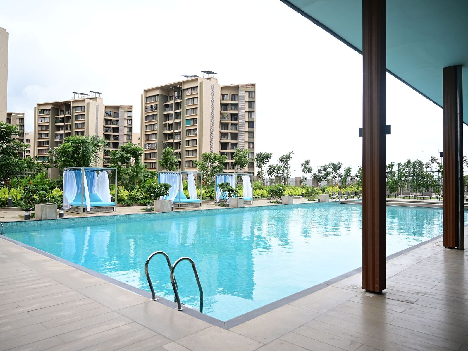 image of the swimming pool taken from under a shed with buildings in the backgroun at club charholi, pune
