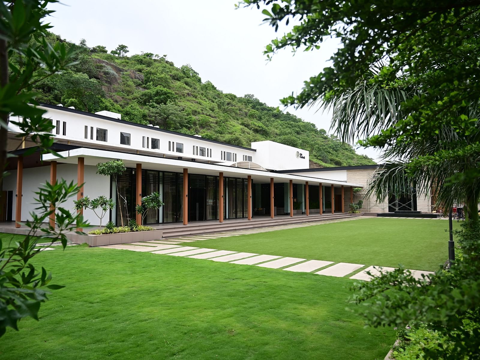 A modern building with a long, covered porch , backed by a wooded hillside.
