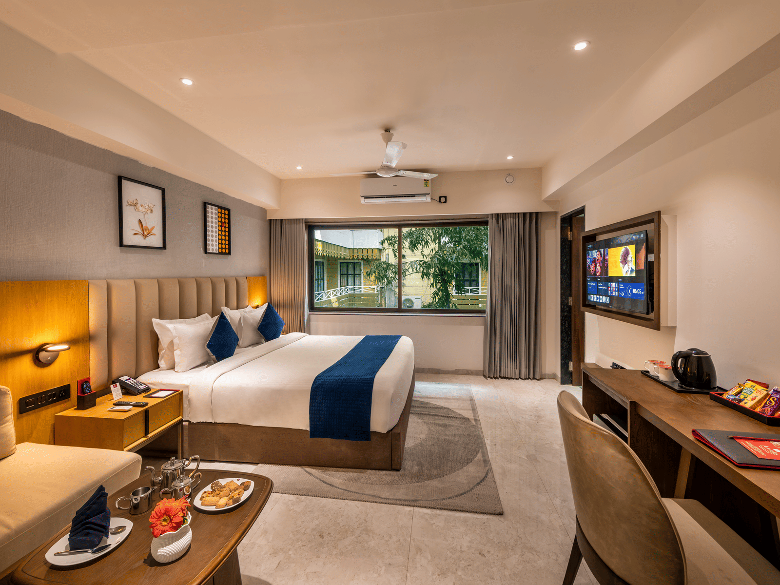 Comfortable stay space with large bed, work desk, and warm lighting at Lords Studio Inn, Jamnagar.