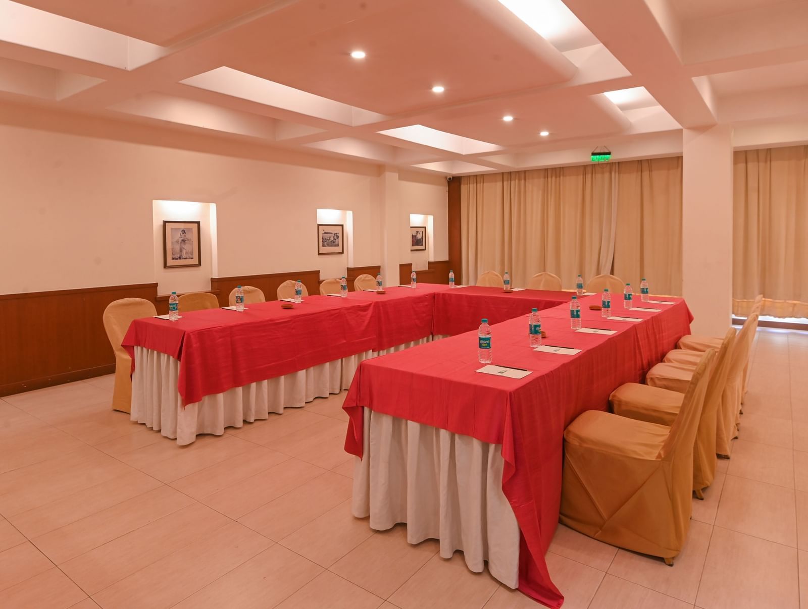 A well-lit conference hall in Vedic Village Spa Resort featuring modern interiors and chairs arranged to one side of two tables.