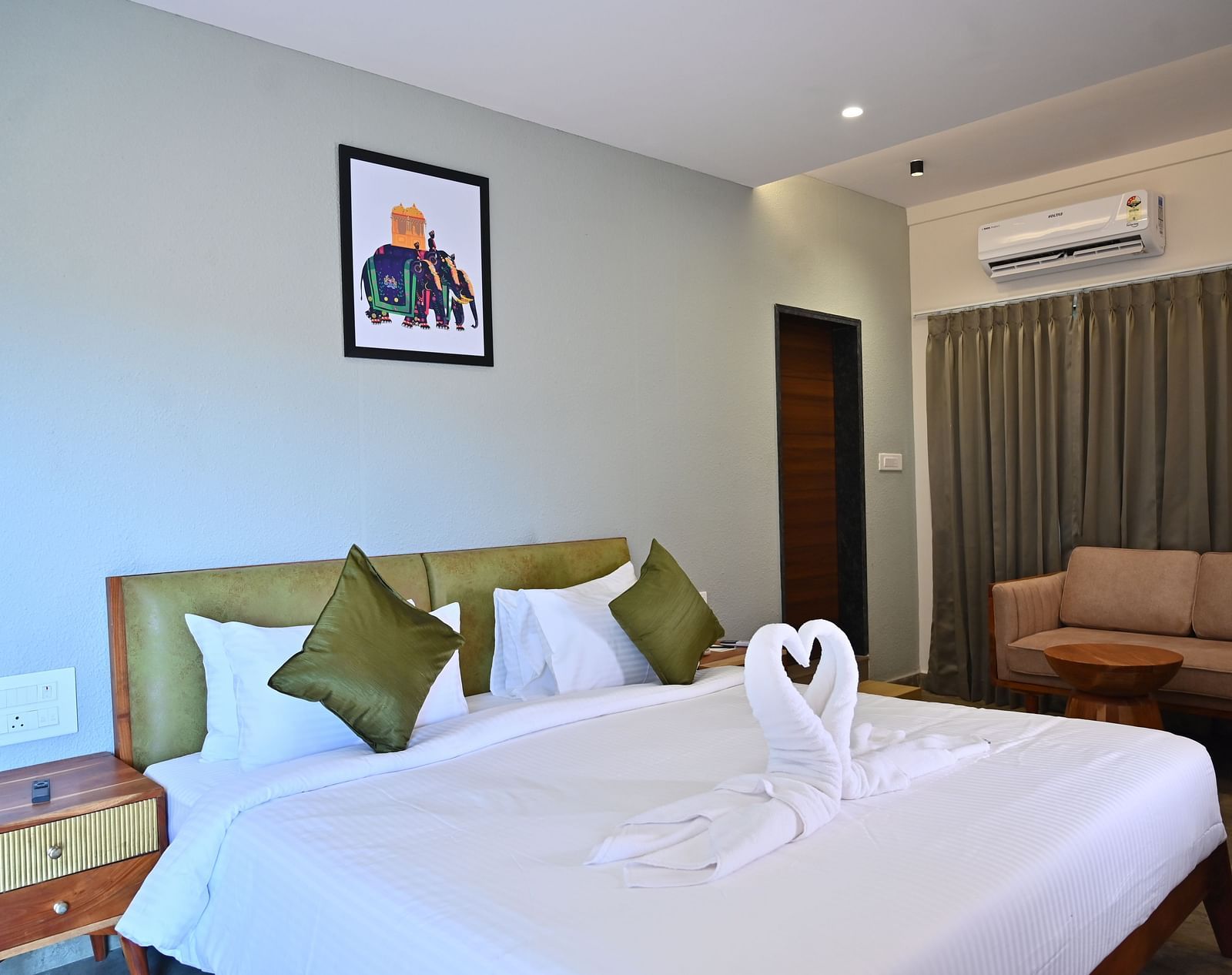 Club Suite featuring a large bed with pillows, a towel swan, a sofa, and warm wooden furniture at TGI Livancia Hillside