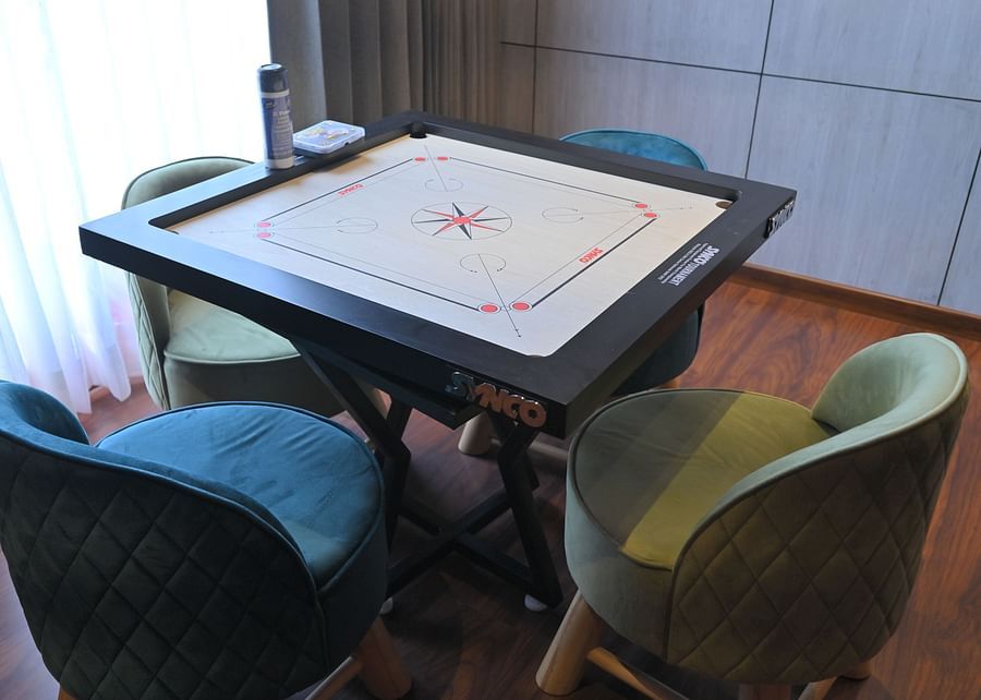A carrom board table with four chairs on each side, in a bright room - Clarks Safari, Haridwar