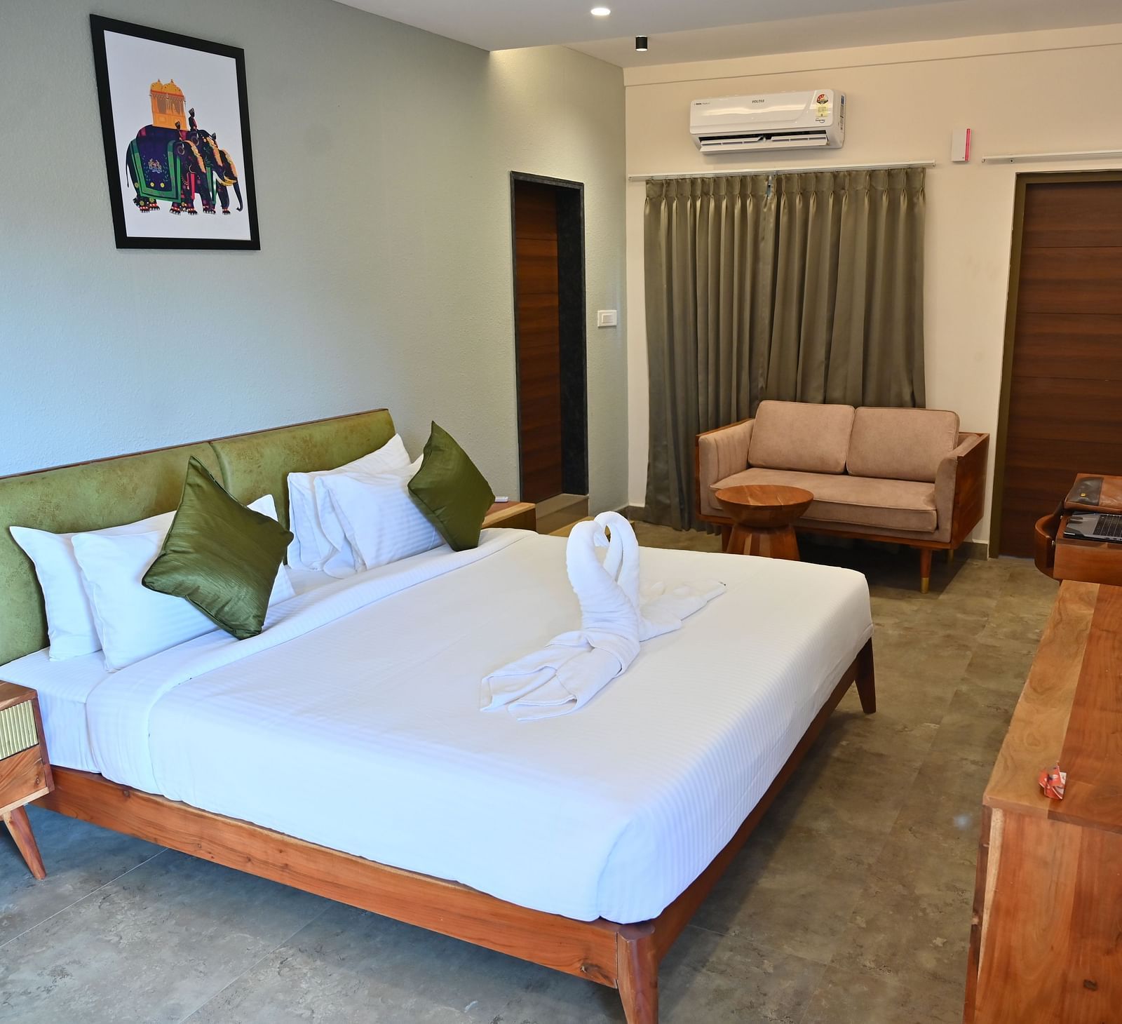 Spacious suite with a large bed, pillows, a sofa, and a wooden desk with modern amenities at TGI Livancia Hillside