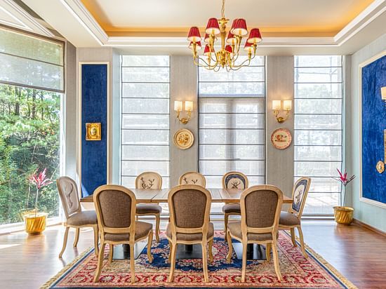 Sophisticated dining room at The Manor Wellness & Sports Hotel - rich blue accents, crystal chandelier & traditional décor with Persian rug.