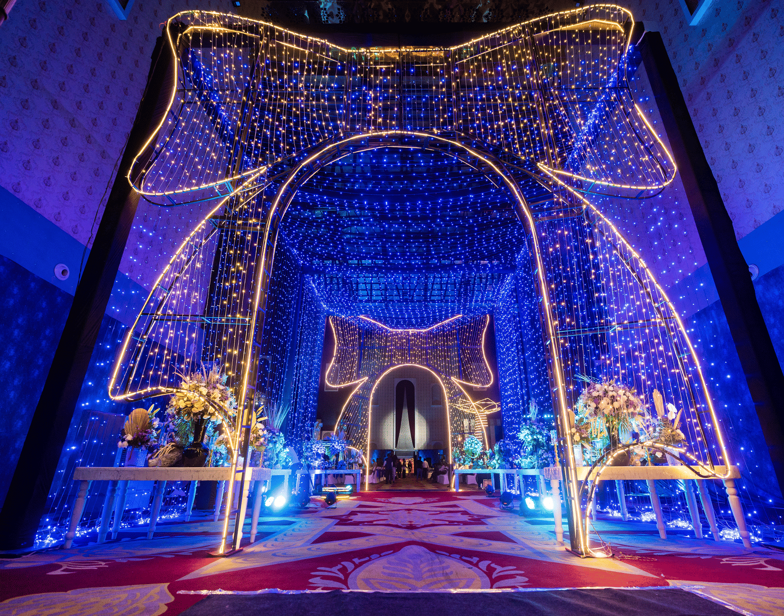 Brightly illuminated stage or entrance archway with elaborate blue and gold lighting and a sparkling curtain effect at Hotel Hukam's Lalit Mahal.