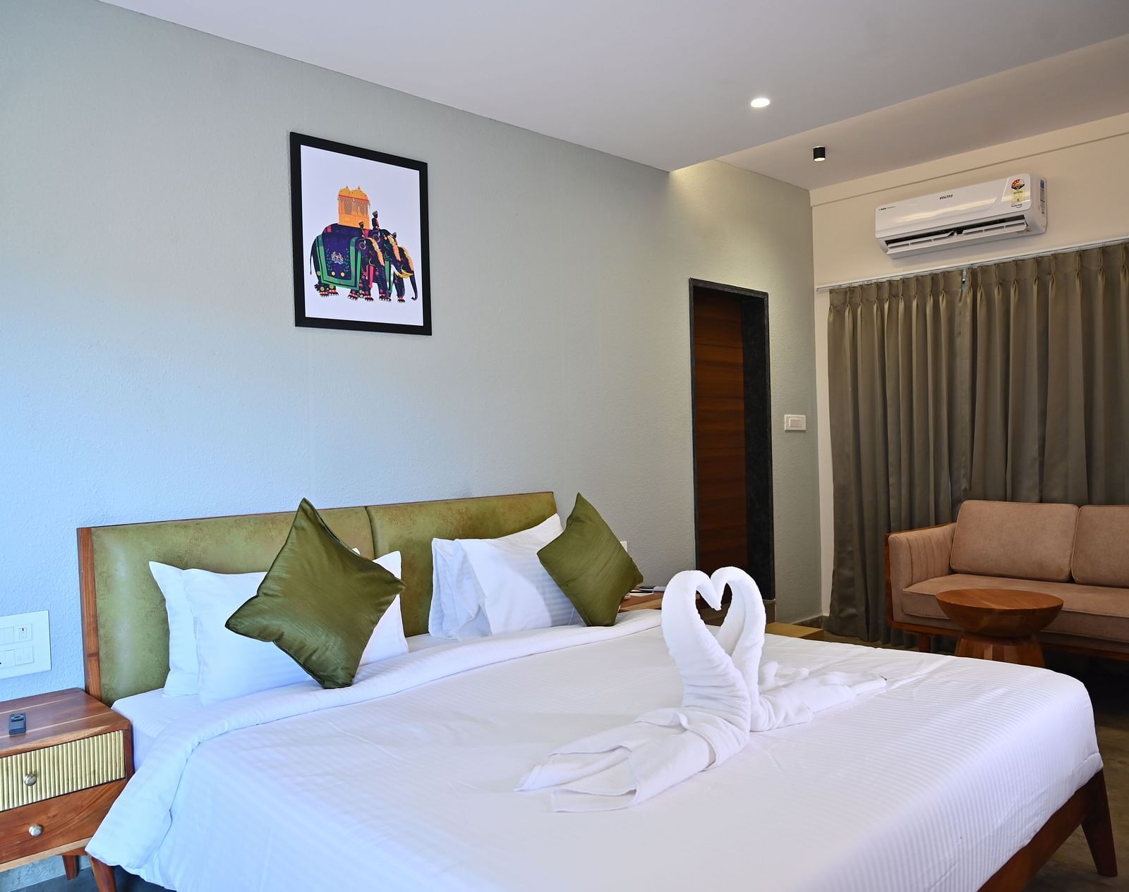 Club Suite featuring a large bed with pillows, a towel swan, a sofa, and warm wooden furniture at TGI Livancia Hillside