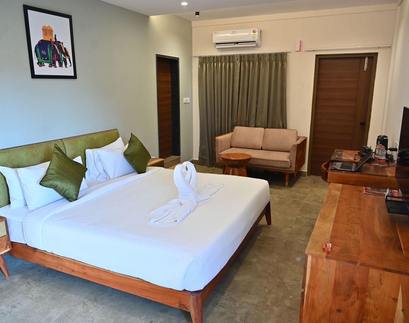 Spacious suite with a large bed, pillows, a sofa, and a wooden desk with modern amenities at TGI Livancia Hillside