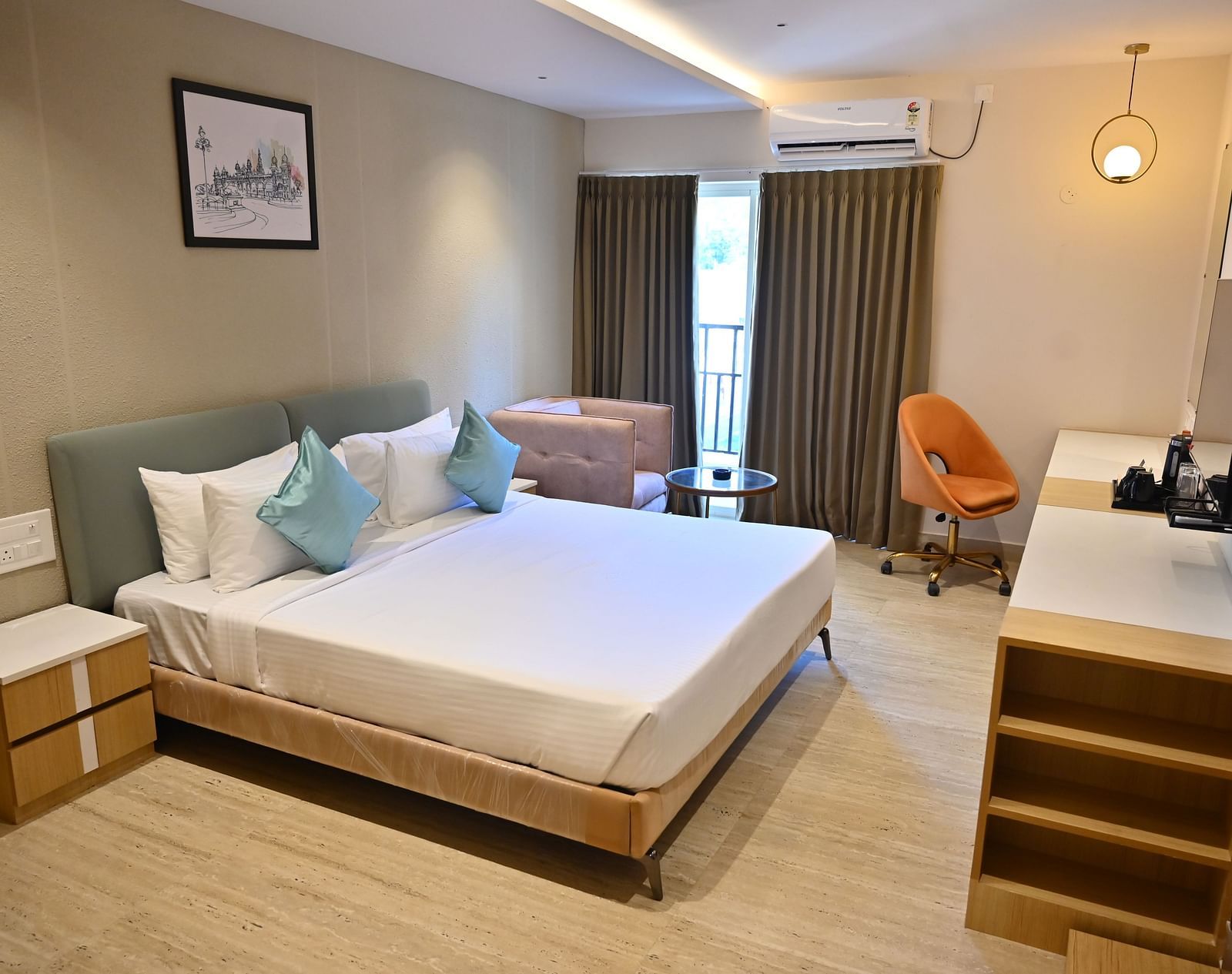 Premium Room featuring a large bed with blue and white pillows, a modern desk, and an orange chair at TGI Livancia Hillside