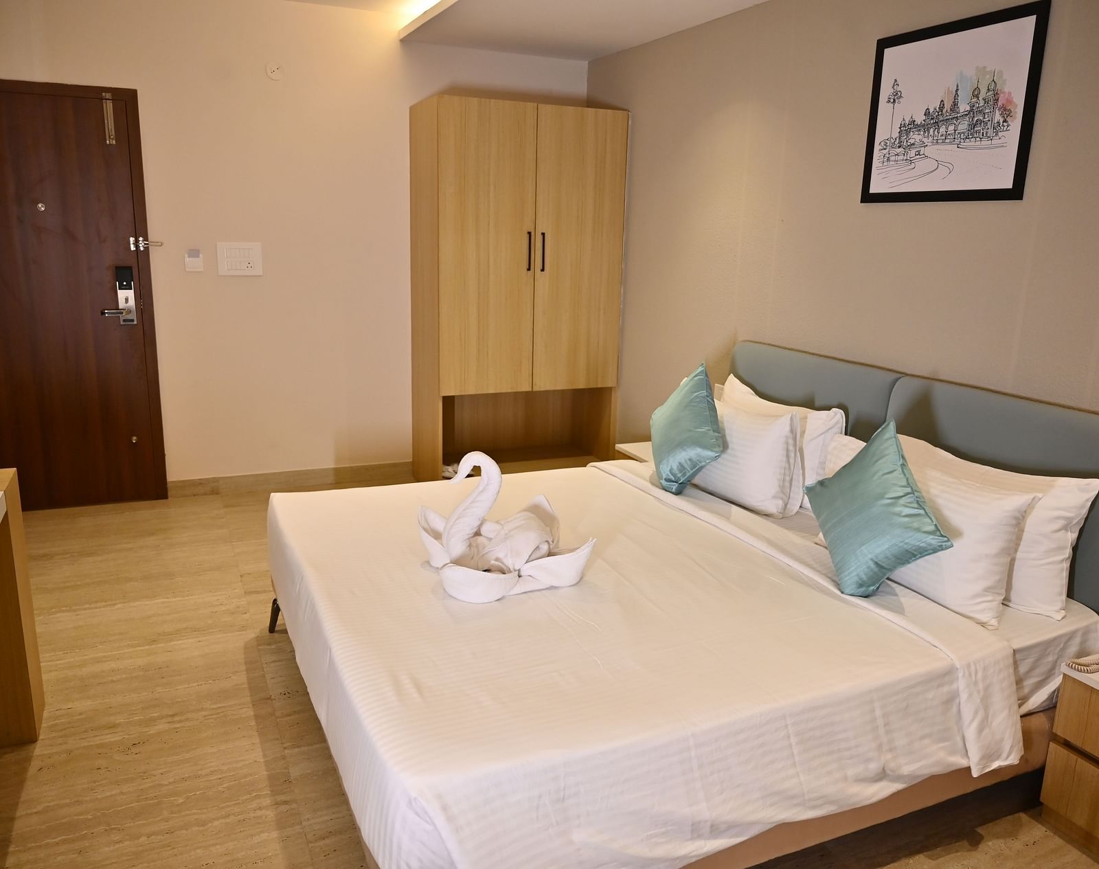 A well-lit hotel room with a neatly made bed, a wardrobe, and a wooden door along with swan-shaped towels adorn the bed at TGI Livancia Hillside