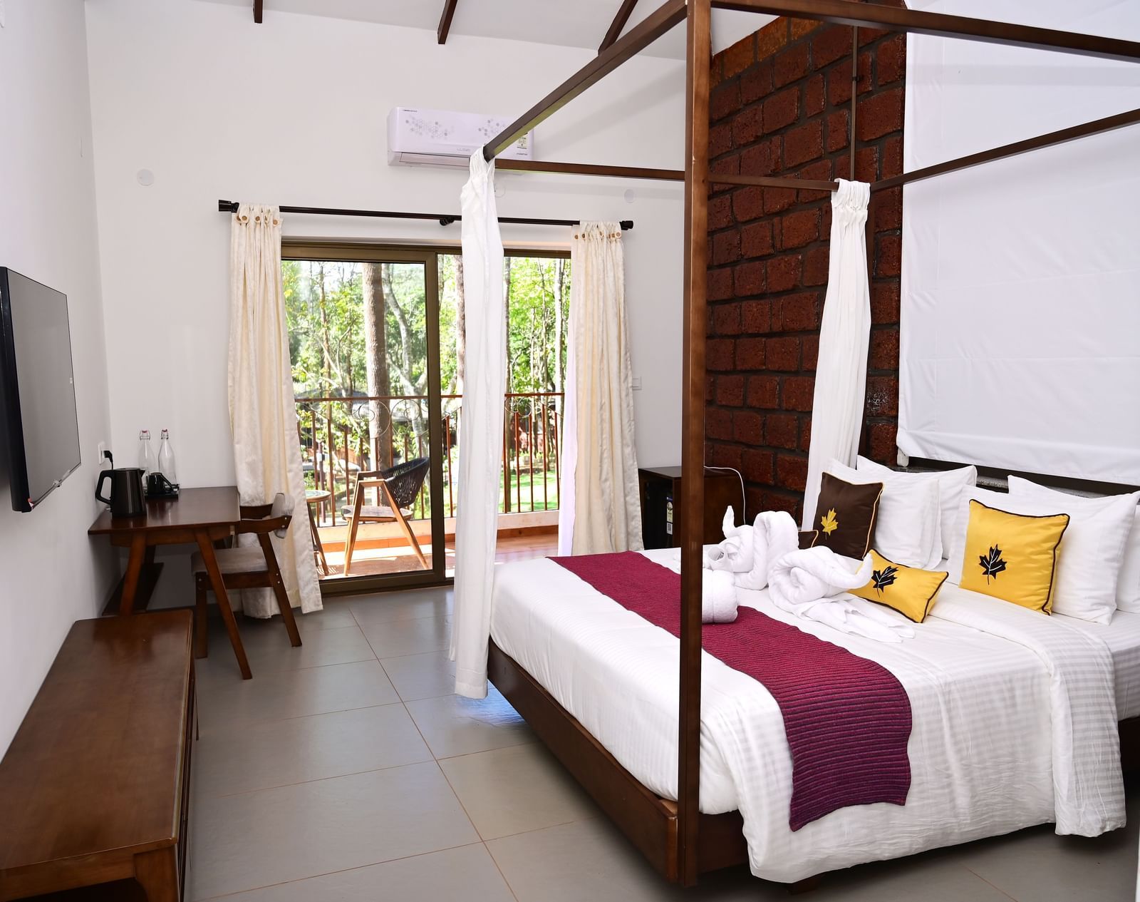 Bedroom at TGI Redolent Resort with a king bed, cabinet, TV, and a  glass door leading to the balcony.