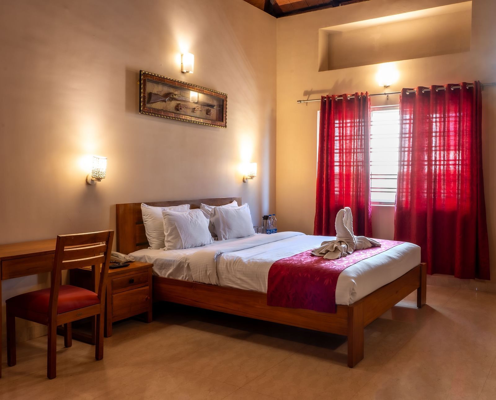 Attic Villa includes a wooden bed with white linens, red curtains, a writing desk, and wall-mounted artwork | Woodstock Resorts, Coorg