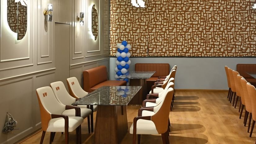 Modern dining room with long tables, soft lighting, and a patterned accent wall at Pride Elite Raipur.