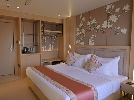 A side view of the bedroom with flower-painted walls, featuring a bed and elegant decor at Clarks Collection Grand Sapphire, Ajmer.