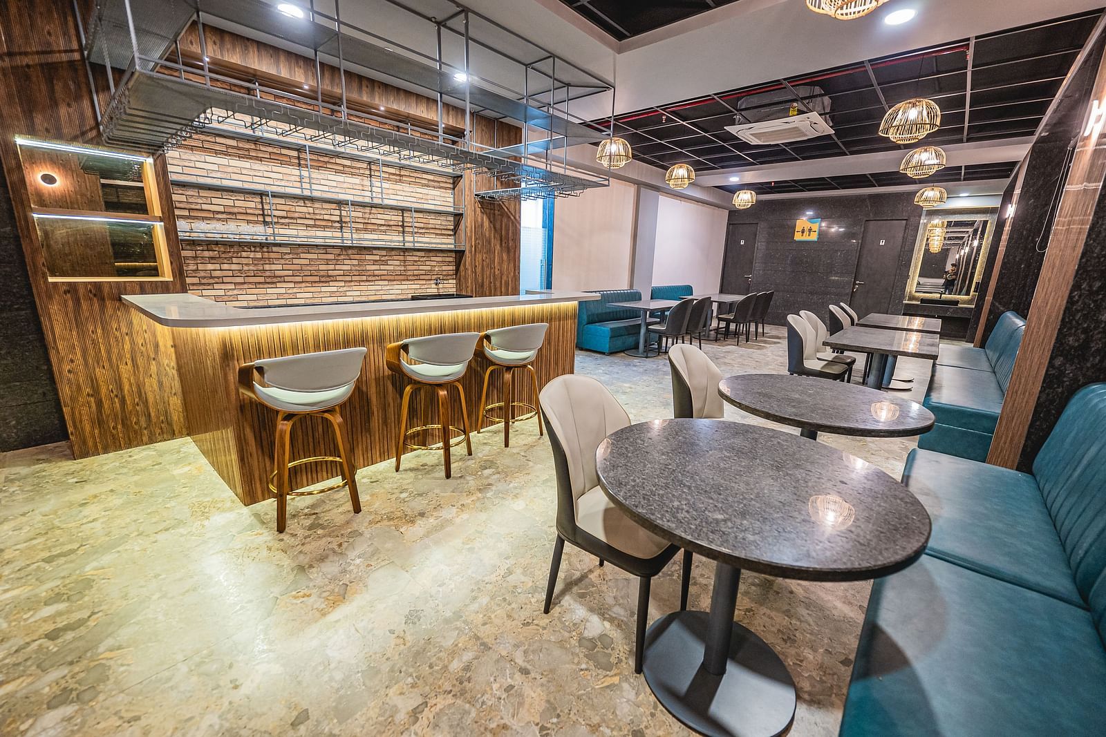 A cosy café corner with round tables and upholstered chairs, featuring warm lighting at Lotus Leaf Boutique Hotel.