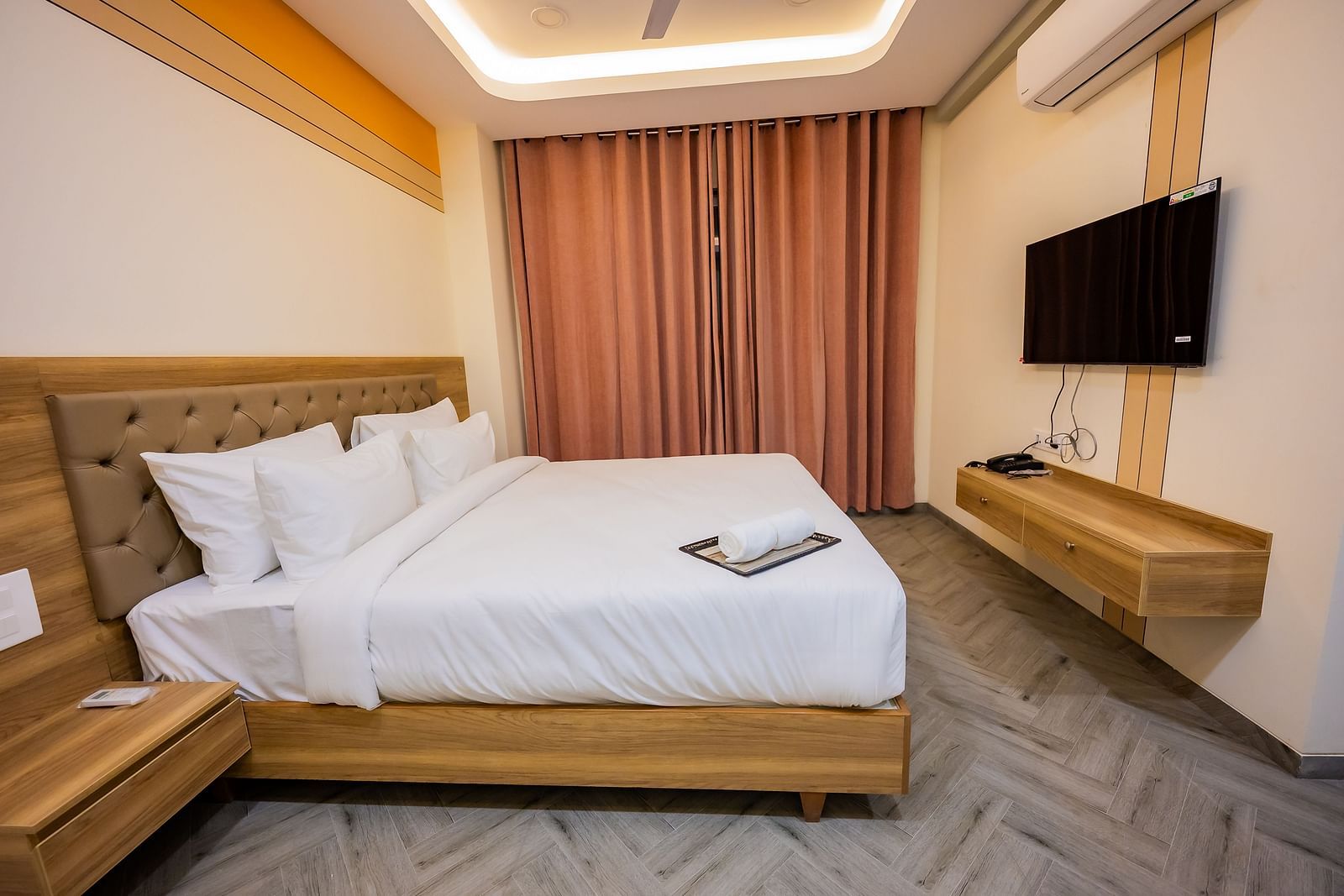 A modern hotel room at Lotus Leaf Boutique Hotel with a large bed, curtains, and a mounted TV.