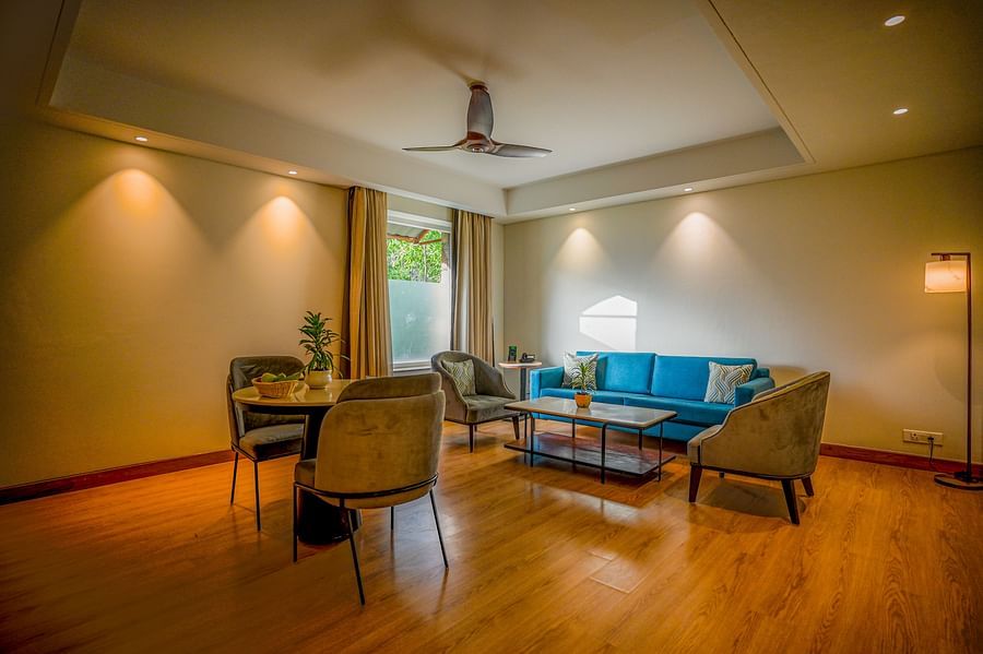 Similar to the previous image, this view shows a slightly different angle of the hotel suite with a round dining table and three chairs, and a teal sofa and coffee table - Ananta Spa and Resorts, Pushkar