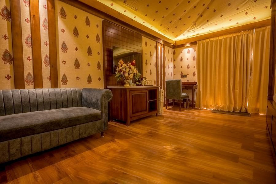 A Premium Duplex text room featuring a  sofa, a cabinet table with flower vase, mirror attached on the wall, and a work desk and chair at The Baagh Ananta Elite, Ranthambore