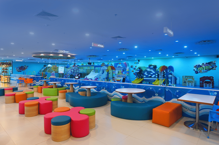 Indoor playground with blue flooring, colorful seating, and various play areas, designed for kids.