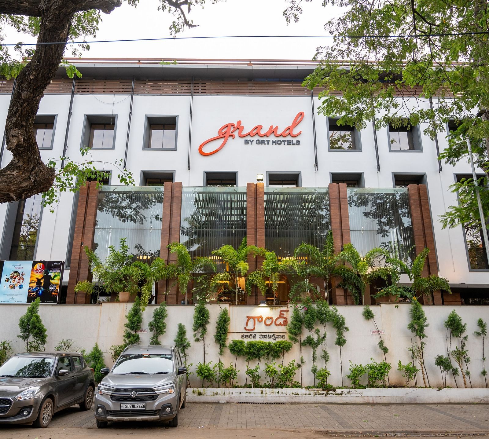 Parking space of Grand Kakinada by GRT Hotels covered with plants and trees