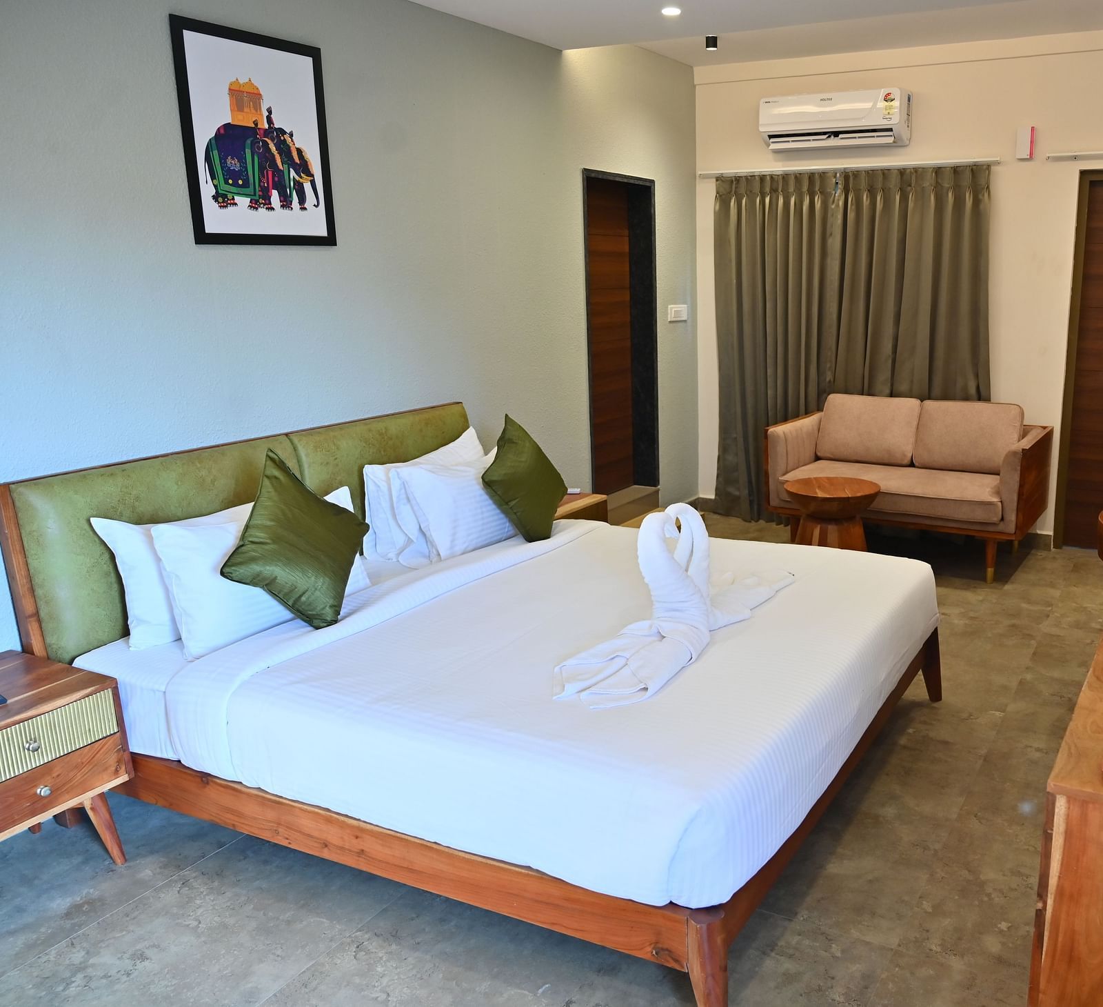 Spacious suite with a large bed, pillows, a sofa, and a wooden desk with modern amenities - Livancia Hillside