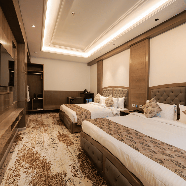 A guest room featuring two single beds with patterned headboards and modern wall-mounted television at Ananta Express, Katra.