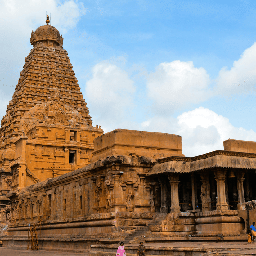 A facade view of Brihadeeswarar Temple in Thanjavur in all its glory with people walking next to it and blue sky in the background, as seen during the summer in Thanjavur.
