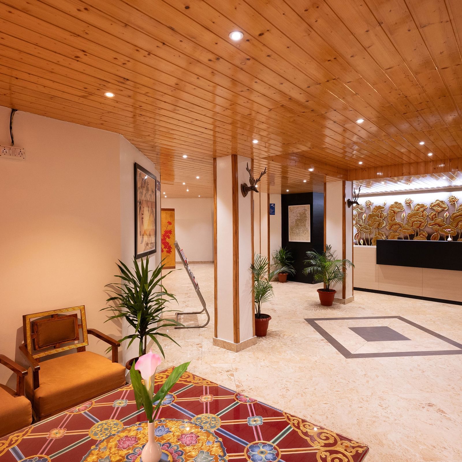 A lobby area with wooden interiors, vibrant decor, and a view of the reception desk at Avianna Hungry Jack, Gangtok.