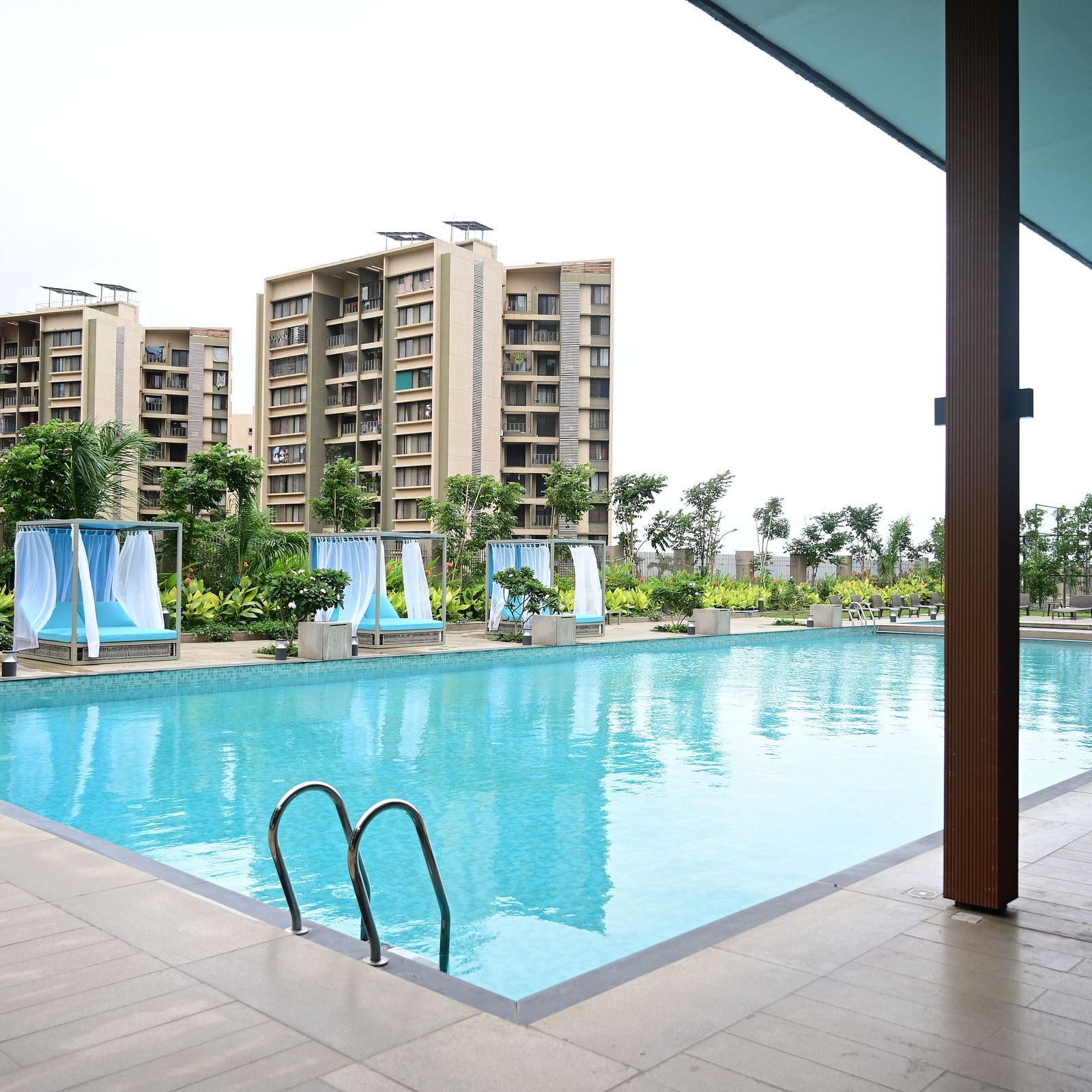 image of the swimming pool taken from under a shed with buildings in the backgroun at club charholi, pune