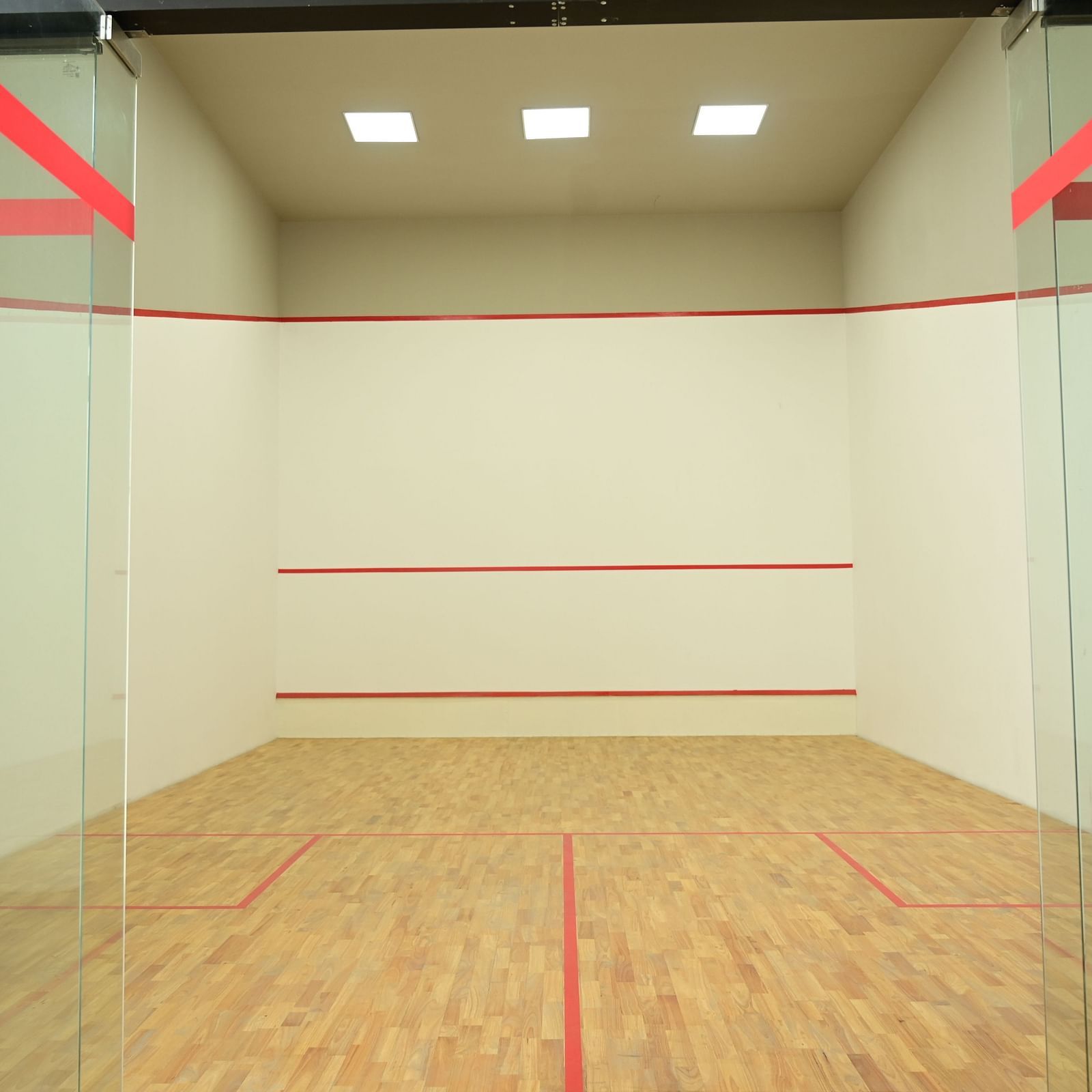 front view image of the squash court with ceiling lights at club charholi, pune