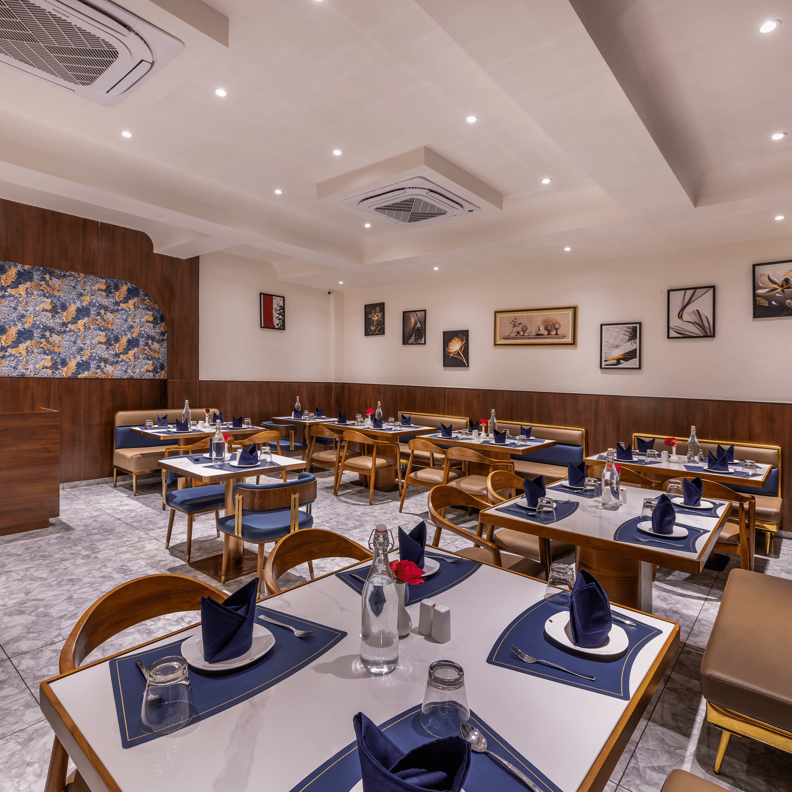 Spacious dining hall with neatly arranged tables set for guests at the restaurant of Lords Studio Inn, Jamnagar.