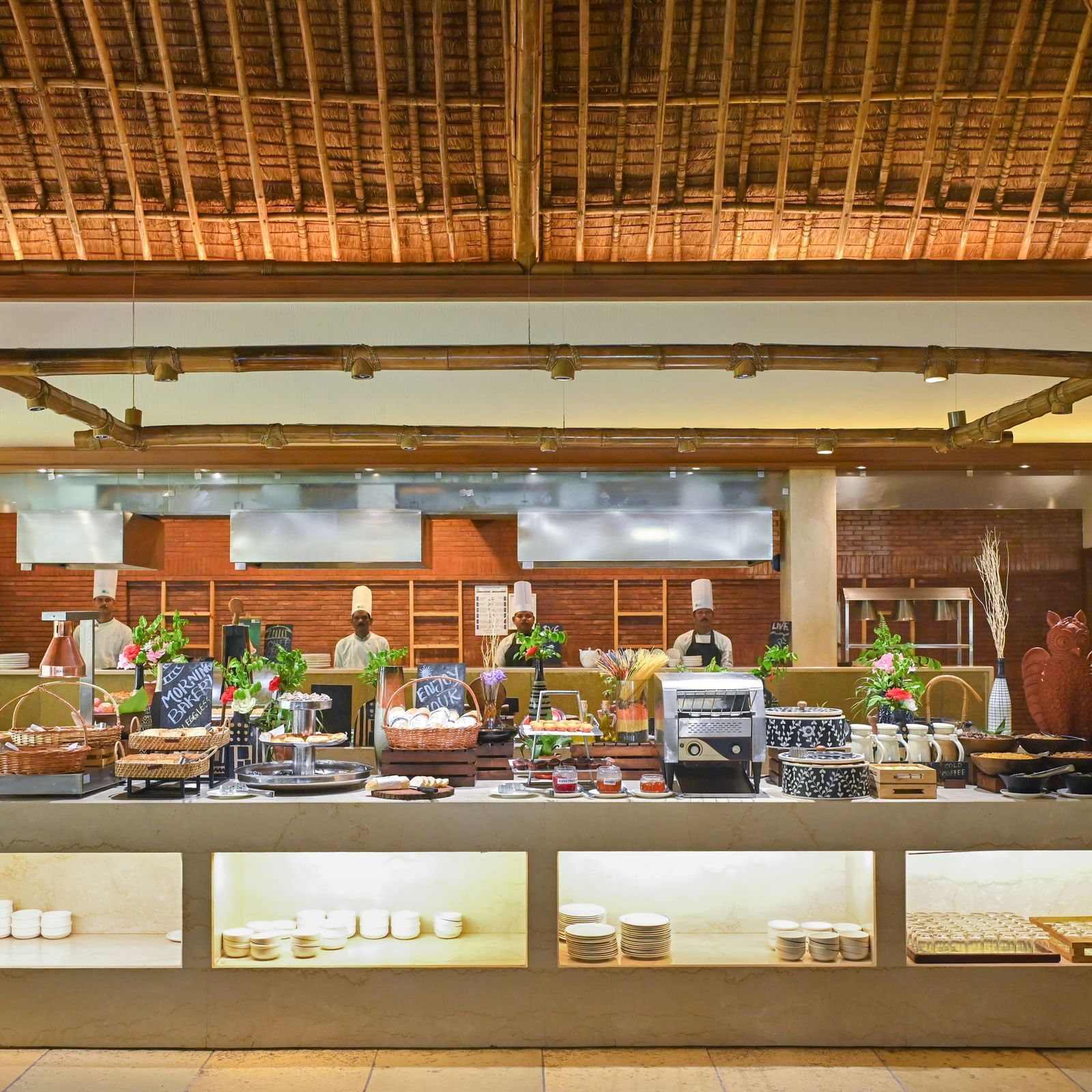 Buffet Counter in Yagna at Vedic Village Spa Resort, featuring high ceilings and chefs lined up behind the counter.