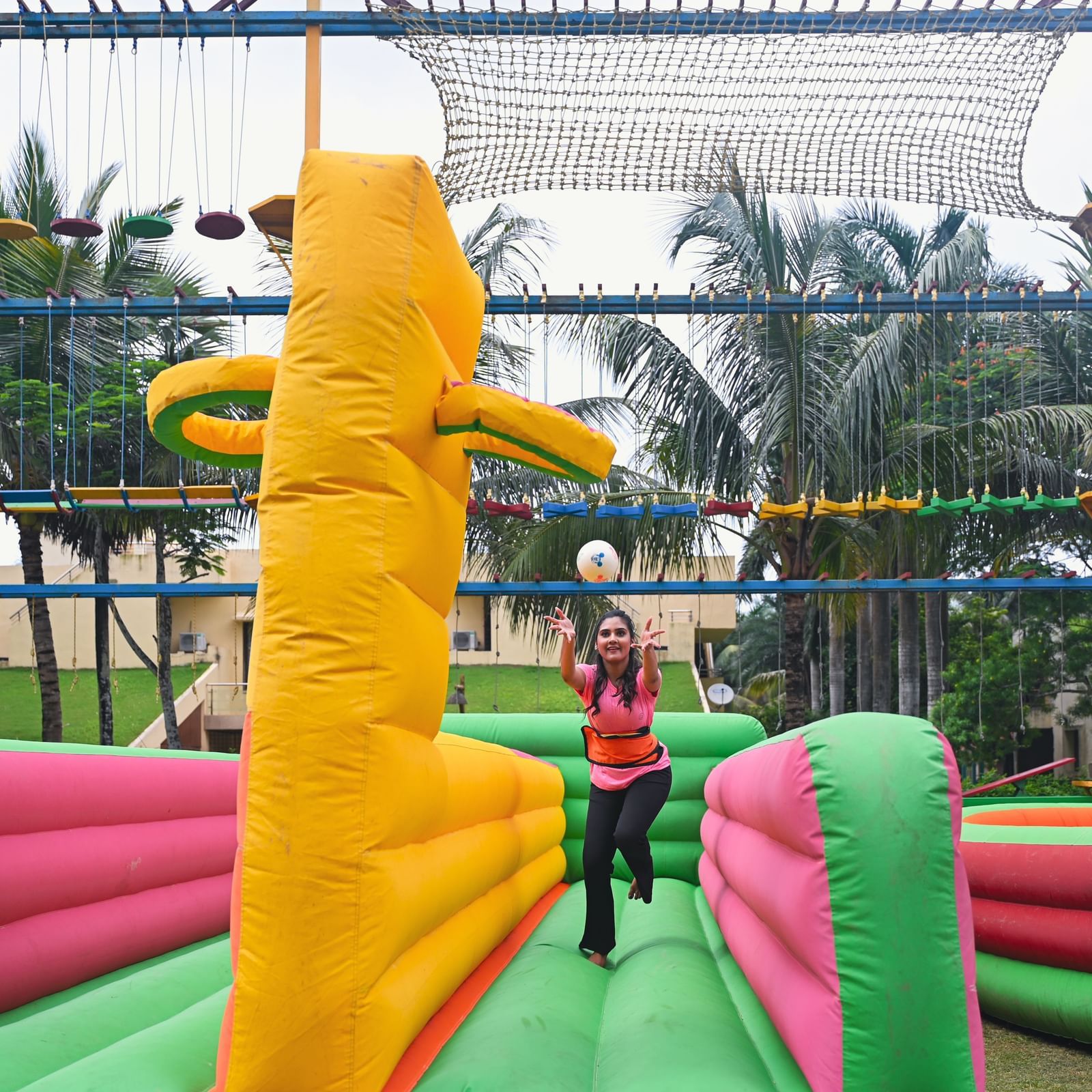 An inflatable obstacle course with yellow and green elements, featuring a person in the background