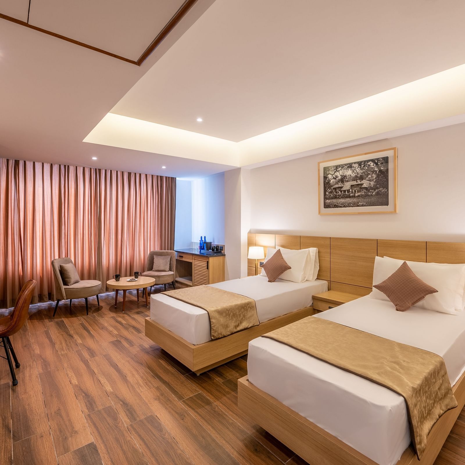 Close up shot of Twin Room at Vishranti Resort, Dehradun featuring twin beds, side table with bed lamp and a work desk.