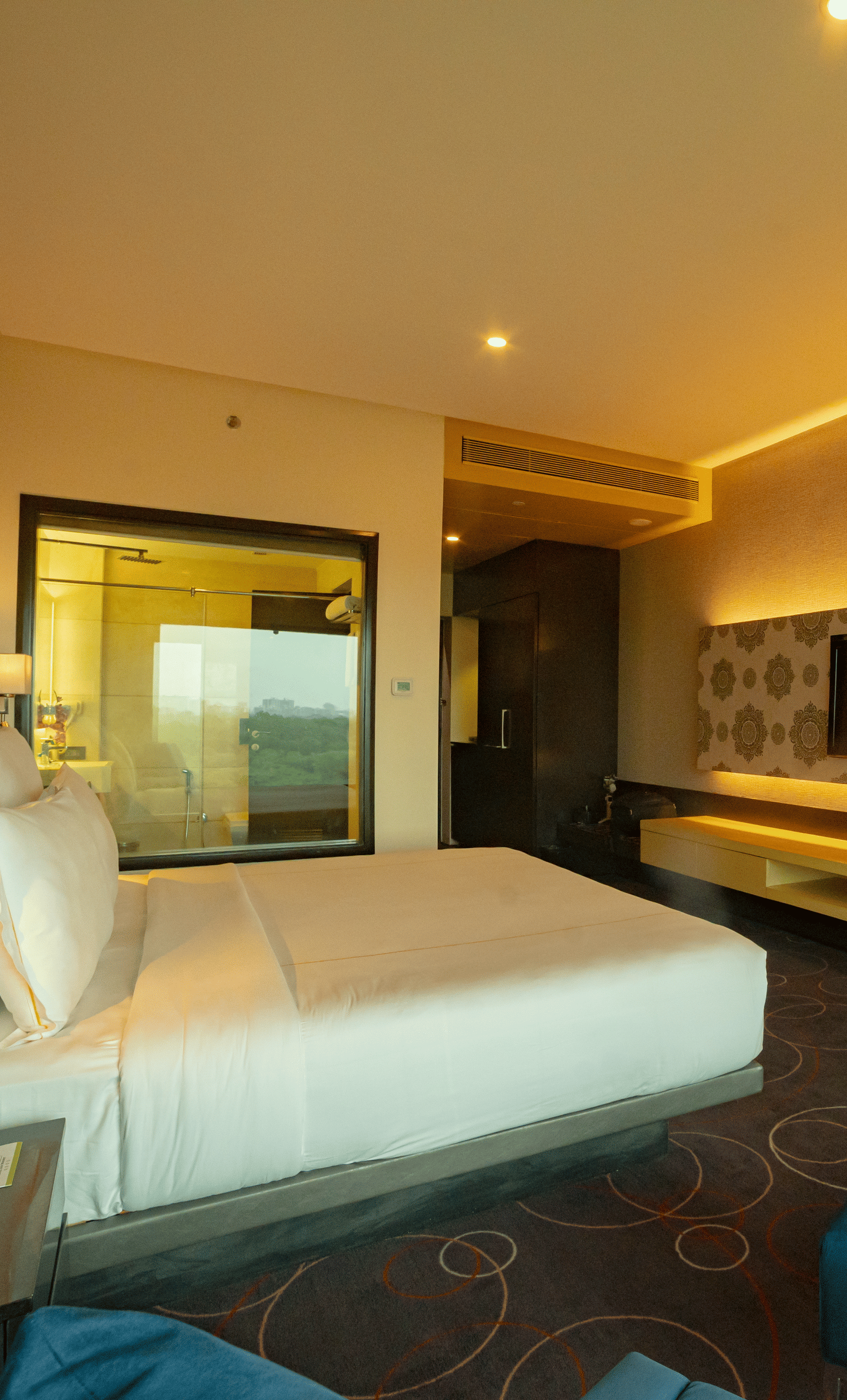Luxury hotel room with modern lighting and blue seating at Narayani Heights Hotel & Resorts, Ahmedabad.