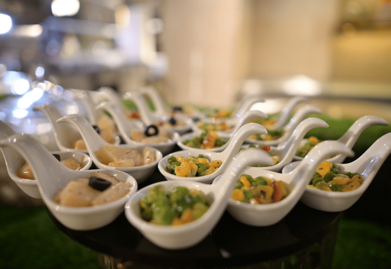 A close-up shot of elegant ceramic spoons filled with assorted canapes and appetisers at Pushkara Resort & Spa.