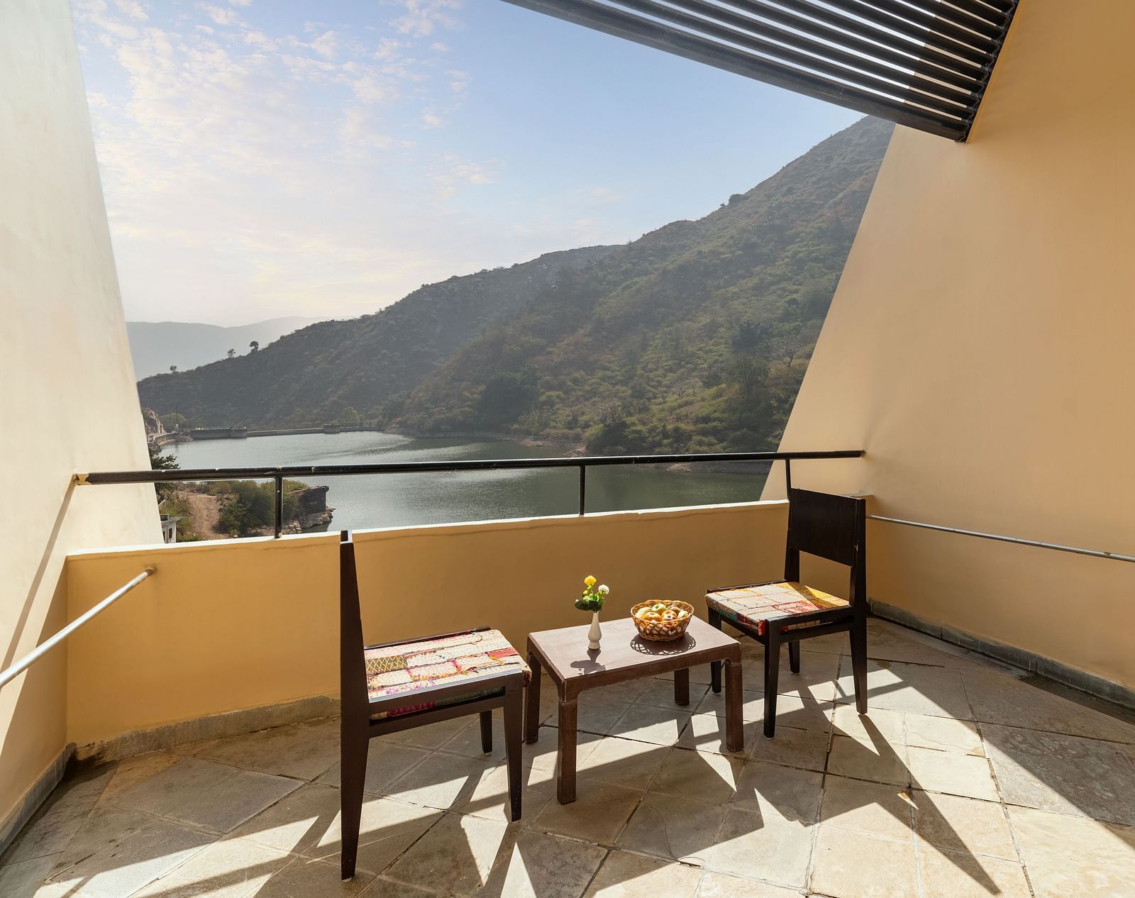 A balcony view with neatly arranged table and chairs under a sunny day - Via Lakhela Resort & Spa