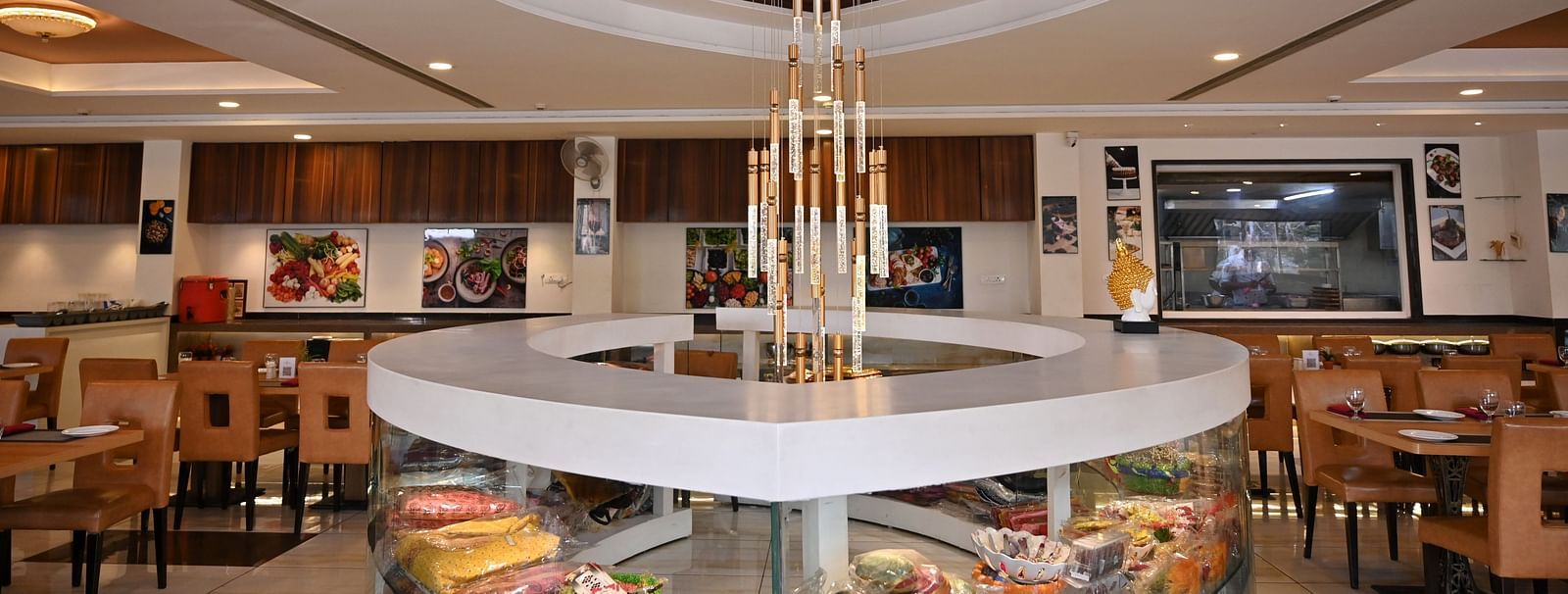 Hotel restaurant interior with circular centre piece display under a modern chandelier - TGI Insignia, Bhopal