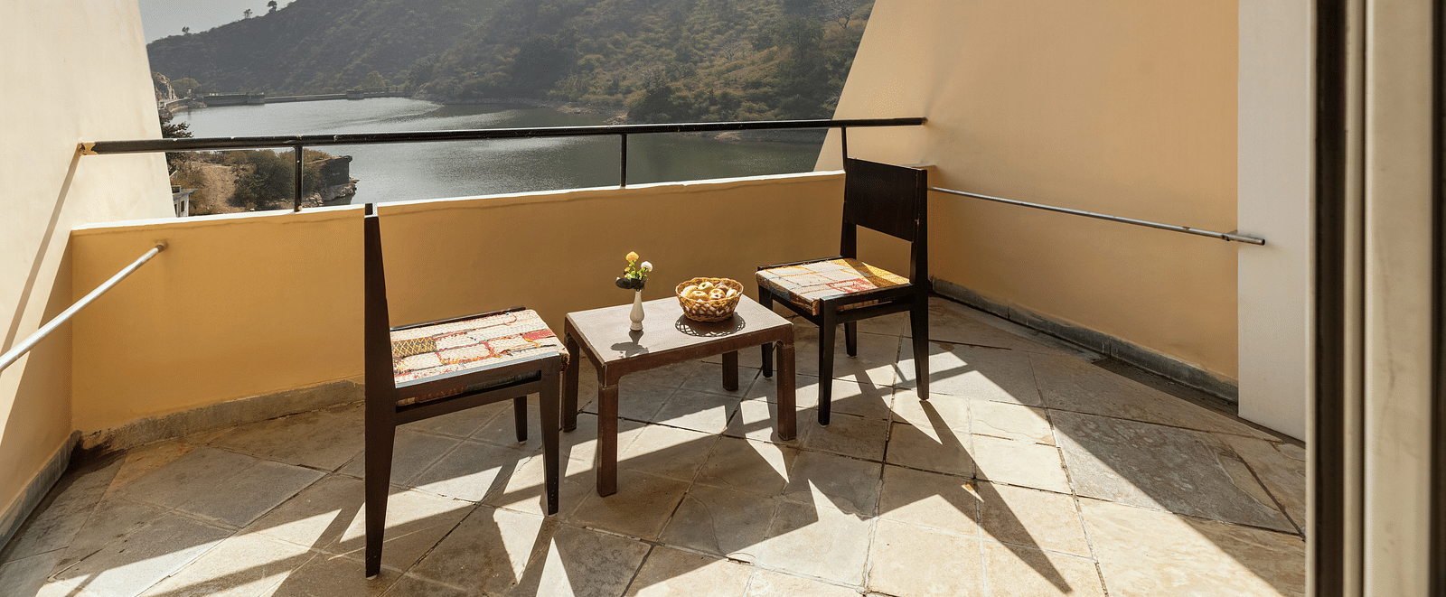A balcony view with neatly arranged table and chairs under a sunny day - Via Lakhela Resort & Spa