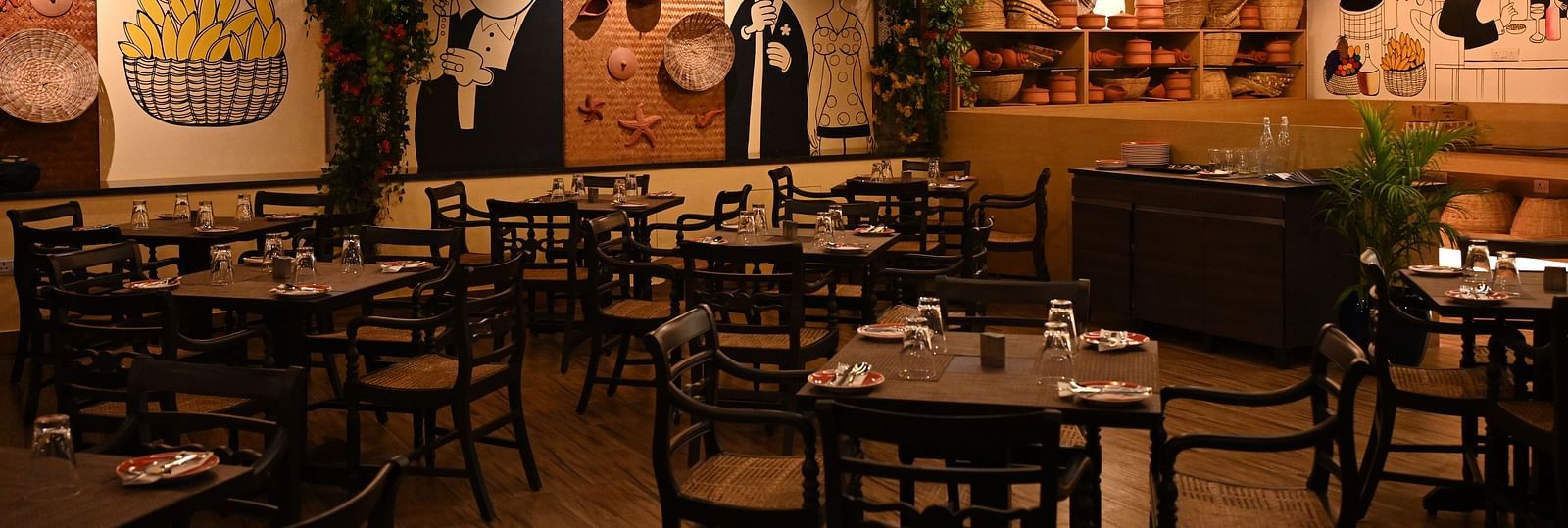 An image of a cafe with several sets of tables and chairs and the walls are  painted with doodles - Essentia Premier Hotel, Chennai.