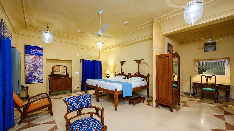 A bedroom with two single beds pushed together, seating, a wardrobe, and a desk at Tijara Fort-Palace - 19th Century, Alwar.