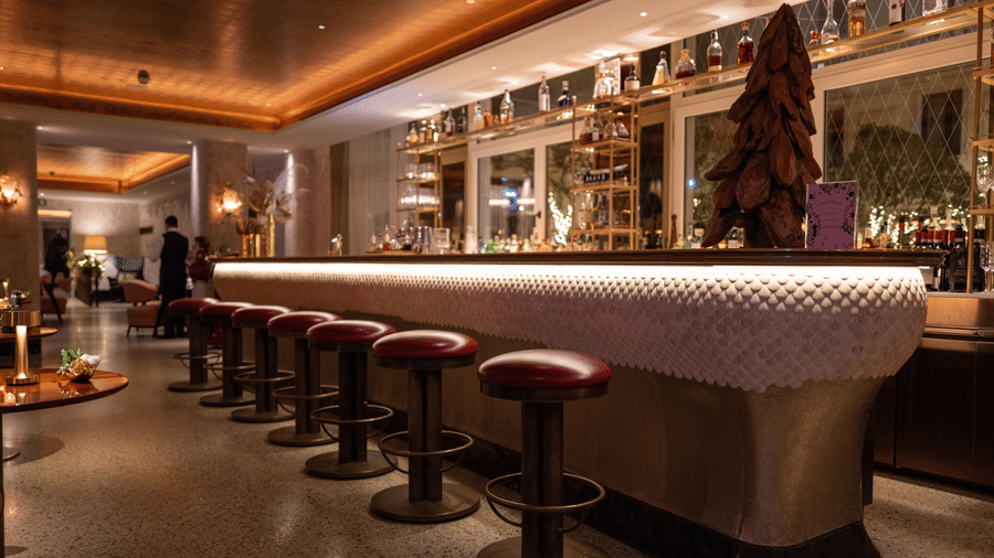 A bar area with a long counter lined with rows of bar stools under warm lighting.