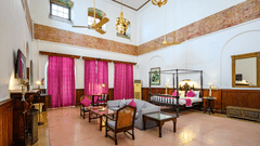 An overview of the Raja Sardul Singh room with sofas, coffee table in front of the tv with king size bed in the background - The Baradari palace