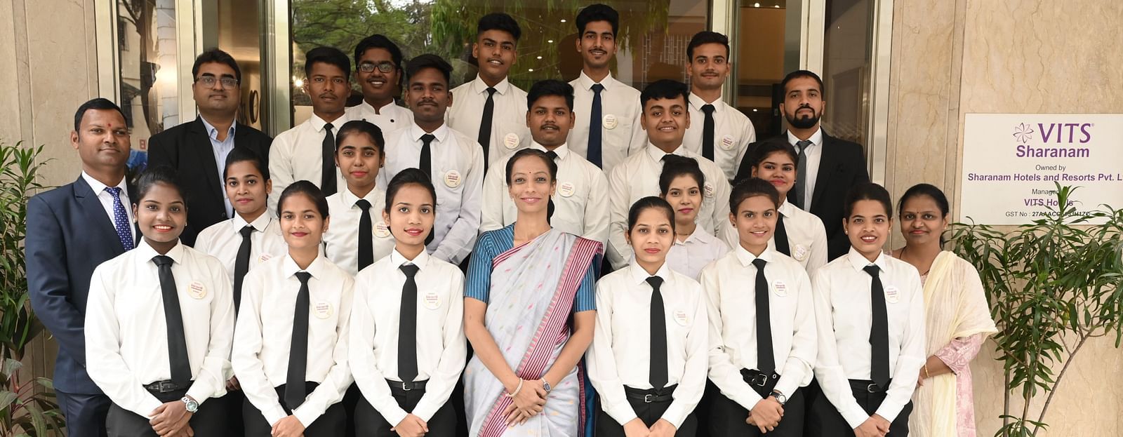 A group photo of hospitality trainees and staff standing at the entrance of VITS Sharanam - Kamats India